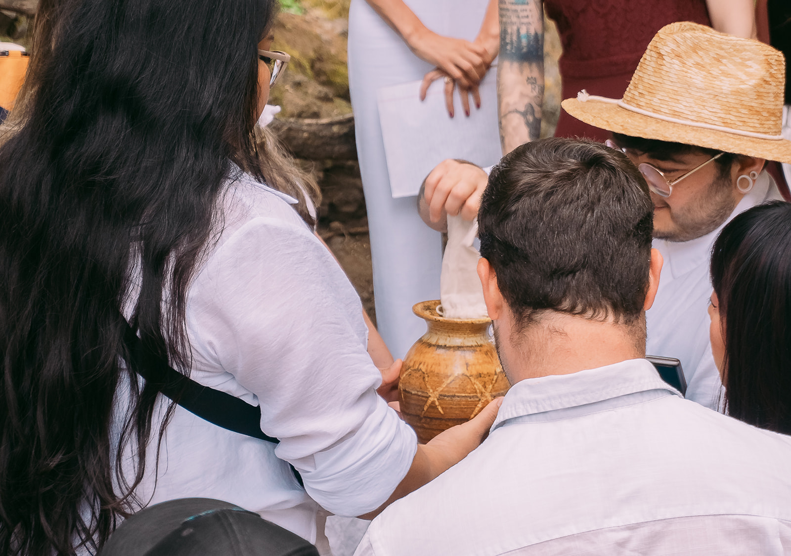 Guests from the small elopement pass around a small pot, ceremoniously pouring soil into it so that the brides can plant a seed for their elopement ceremony.