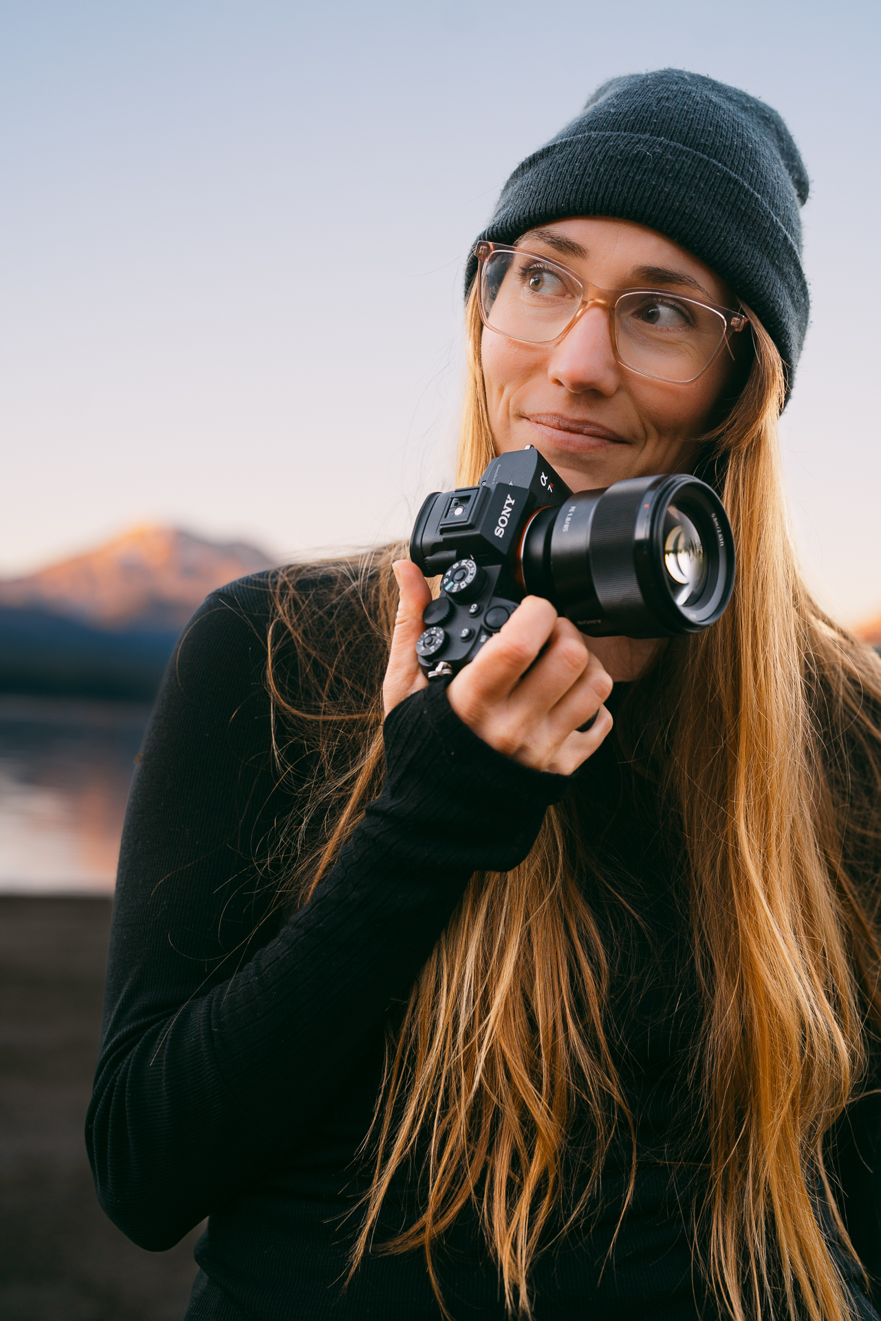 Elopement photographer holding a camera in front of an alpine lake.