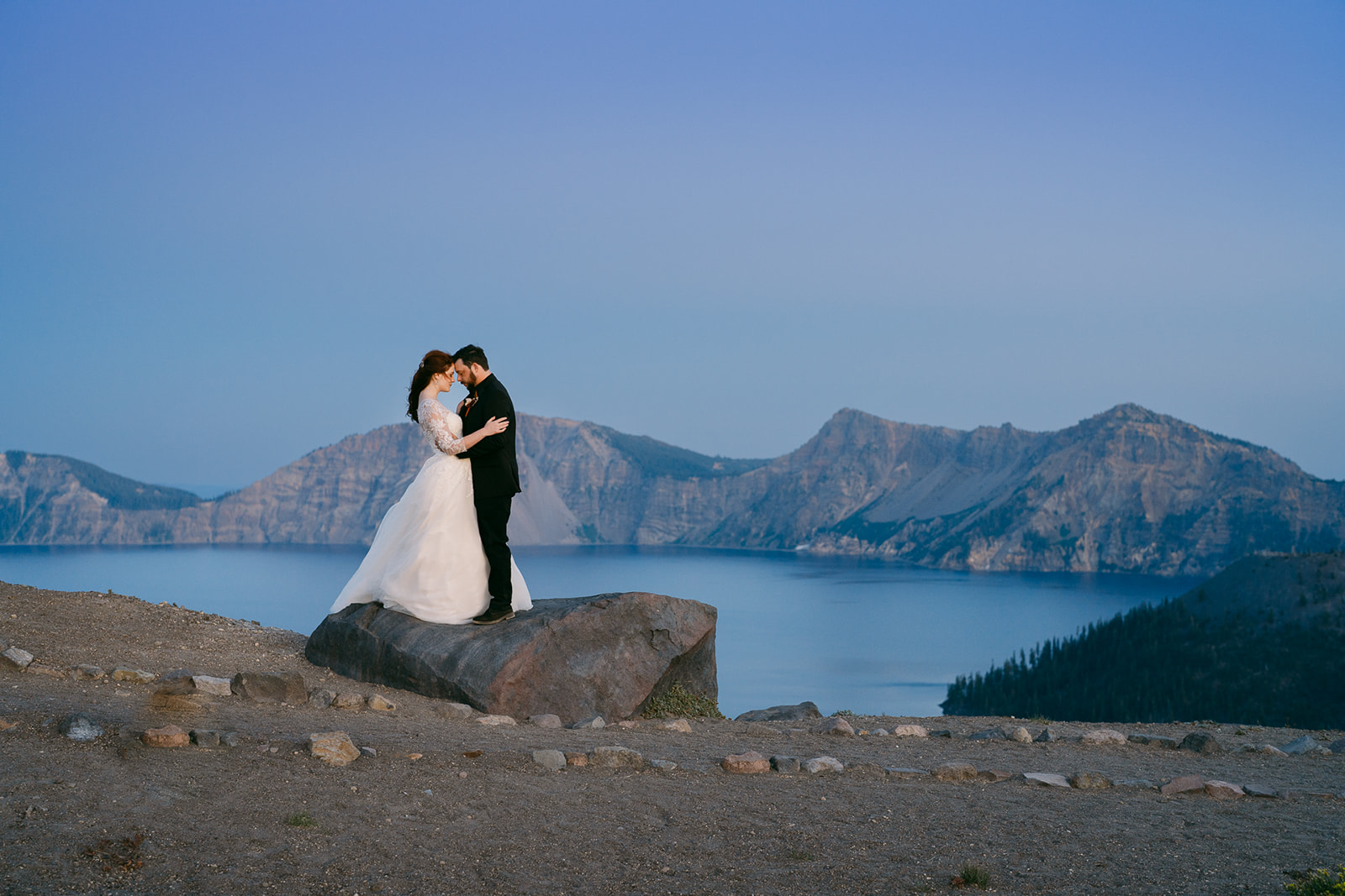 A couple standing together in front of Crater Lake after their vow exchange.